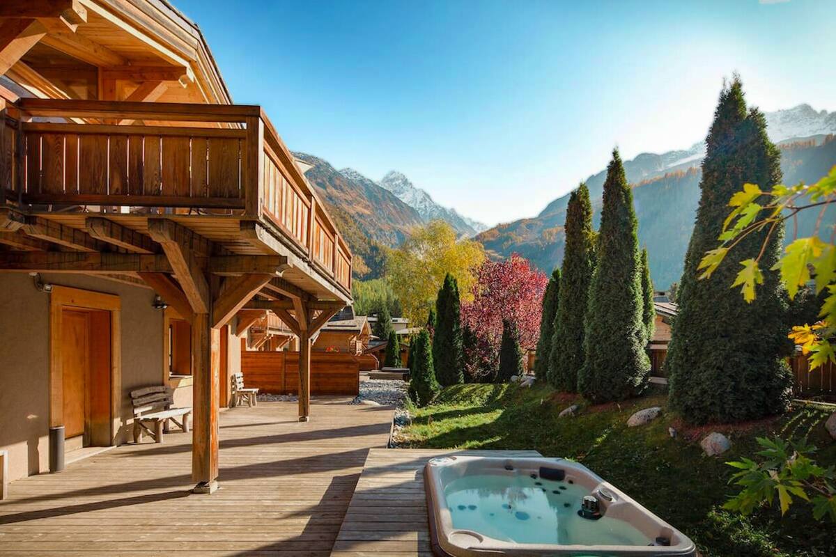 A wooden cabin with a balcony, a hot tub, and a mountain view.