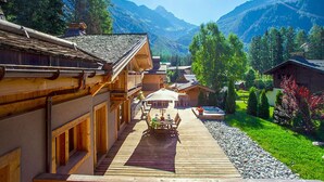 A wooden chalet with a deck, outdoor dining area, and mountain views. - Les Rives d'Argentière (Chamonix-Mont-Blanc)