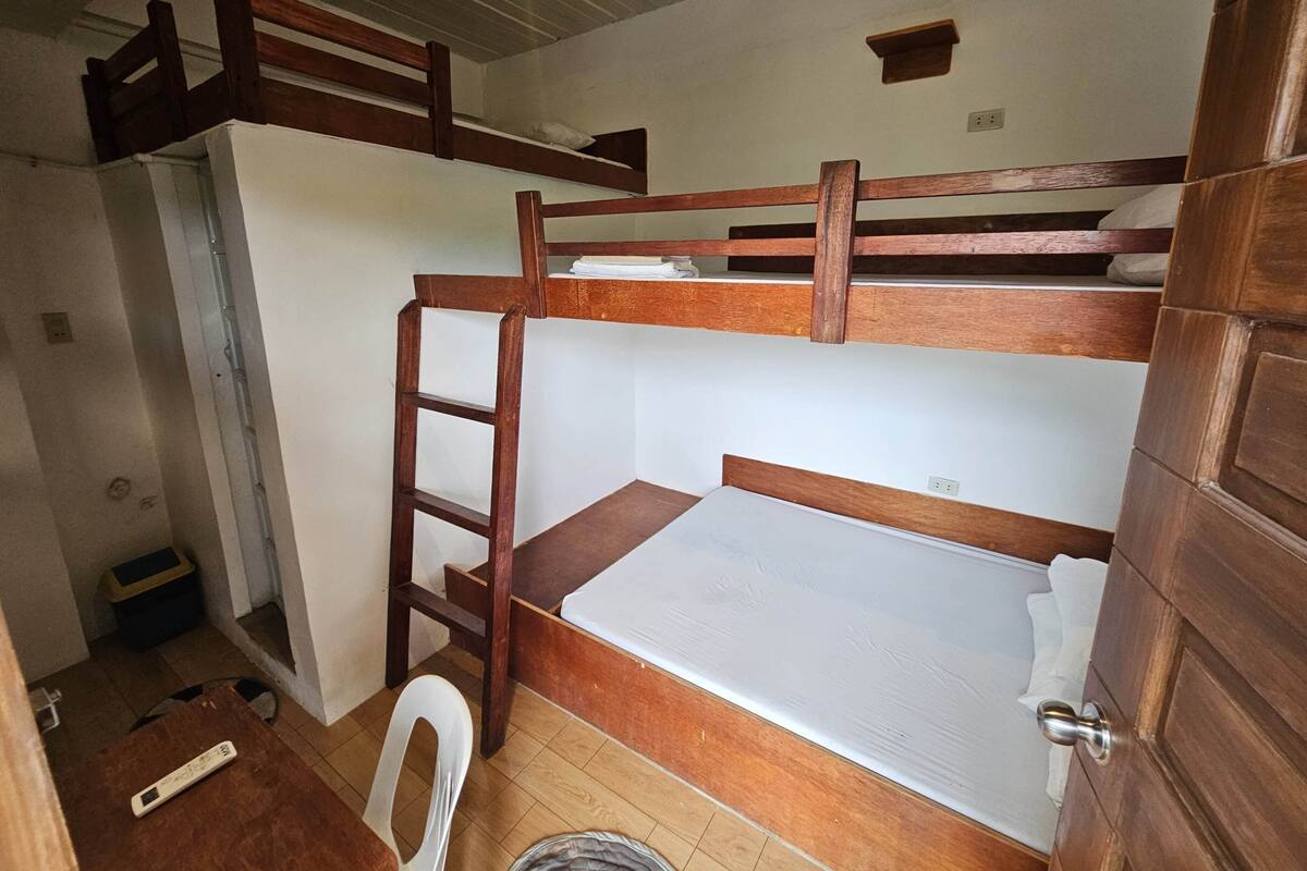 A bunk bed room with a wooden ladder, a single bed, and a chair.