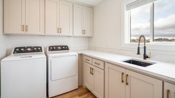 Una cocina con armarios blancos, horno doble, pileta y ventana con vista al exterior.