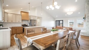 Uma cozinha moderna com armários de madeira, uma ilha central e um espaço de refeições com mesa e cadeiras de madeira.