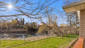 A riverside view with a house, trees, and a clear sky. - Pet Friendly Home with Fishing Access and Fire Pit (Kalispell)