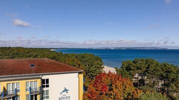 A hotel building with a view of the sea and autumn foliage.