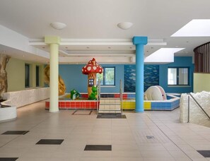 A spacious indoor area with a play zone featuring a large mushroom-shaped structure, a slide, and a pool area. - Ferienpark Rugen Ifa, Binz (Binz)