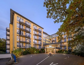 A multi-story hotel with a central courtyard, balconies, and a well-lit entrance.