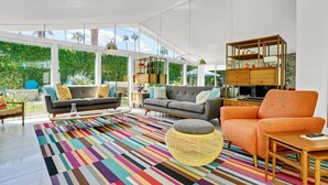 A spacious living room with a large window, a colorful striped rug, and modern furniture. - Twin Palms: Mid-Century Modern with Heated Pool (Palm Springs)