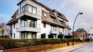 A modern two-story residential building with a flat roof, balconies, and a brick facade.