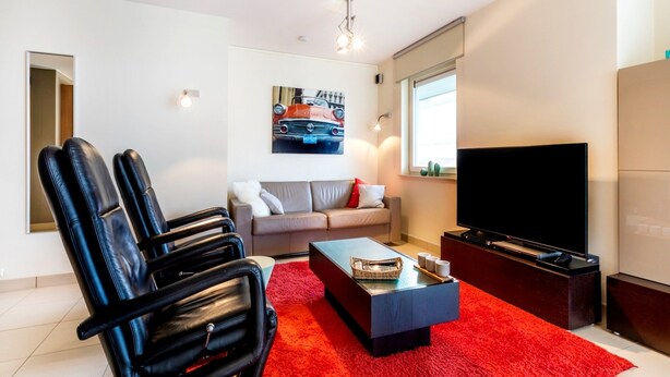 A modern living room with a red carpet, a sofa, a coffee table, and a TV.