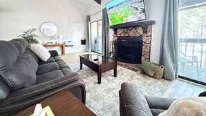Un salon moderne avec une cheminée en pierre, un canapé en cuir et un téléviseur à écran plat fixé au-dessus de la cheminée.