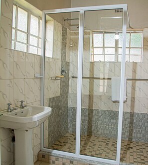 Uma casa de banho com cabine de duche envidraçada, lavatório e paredes revestidas a azulejos.