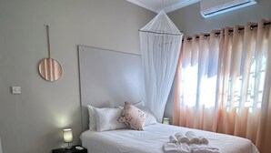 Un dormitorio ordenado con cama, mesita de noche y una lámpara colgante.
