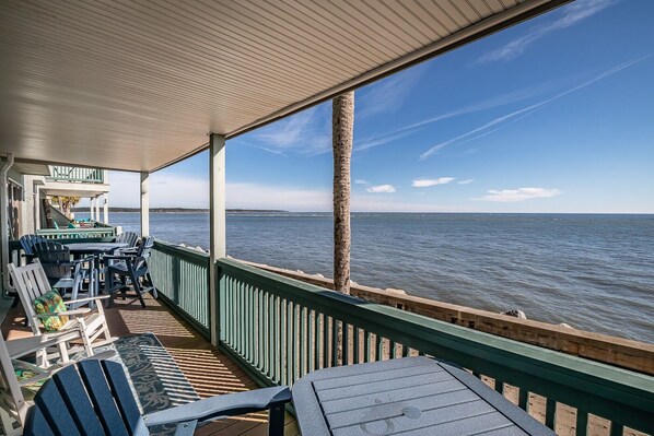 A covered outdoor seating area with a view of the sea, featuring a table and chairs. - Oceanfront, First Floor, Golf Cart Included - 629 Newhaven (Fripp Island)