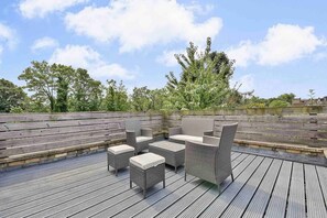 Een terras buiten met rieten meubels en een houten vloer.