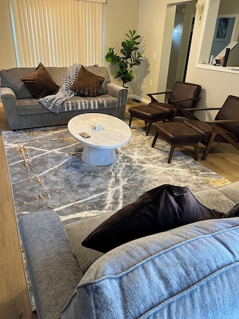 A modern living room with a grey sofa, a coffee table, and brown leather chairs.