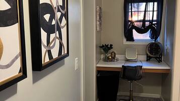 A small office space with a desk, chair, and two framed abstract artworks on the wall.