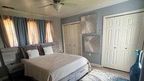 A bedroom with a bed, nightstands, a ceiling fan, a large wardrobe, and a patterned rug. - Charming 3-bedroom house with WiFi, and AC. (Farrell)