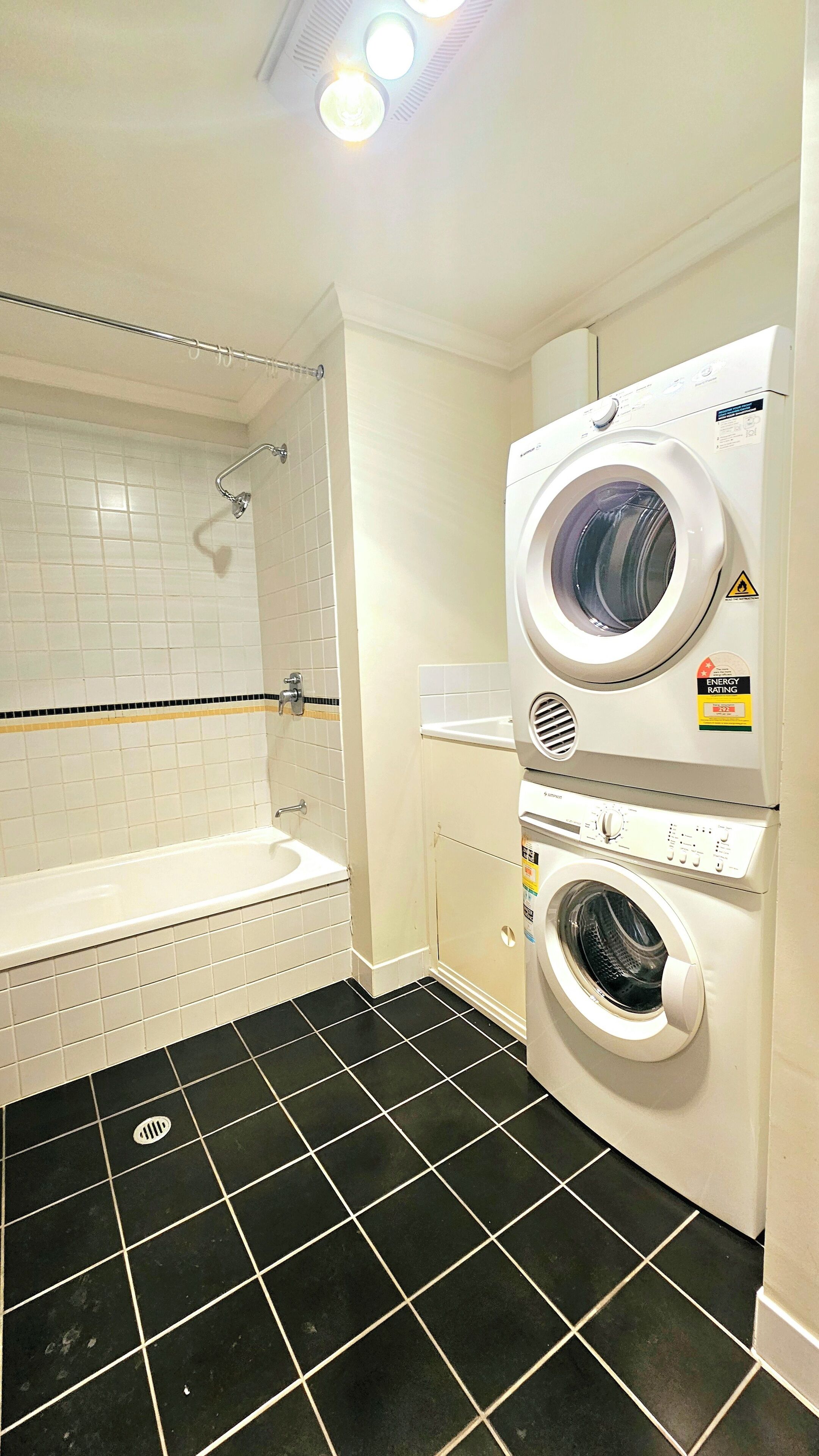 A laundry room with a washing machine, dryer, and bathtub.