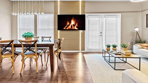 A modern living room with a flat-screen TV mounted on a wall, wooden dining table with chairs, a coffee table, and a sofa. - 4BR house with pool near Disney area (Kissimmee)