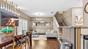 A modern kitchen with a flat-screen TV, wooden dining table, and chairs. - 4BR house with pool near Disney area (Kissimmee)
