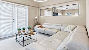 A modern living room with a sectional sofa, a coffee table, and a large mirror on the wall. - 4BR house with pool near Disney area (Kissimmee)