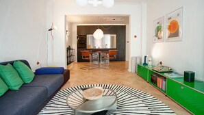 A modern living room with a sofa, a coffee table, and a dining area with chairs and a table.