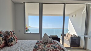 A bedroom with a large bed, a balcony with a view of the sea, and a sliding glass door. - Cartagena Beach Resort 1408 (Cartagena de Indias)