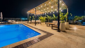 A rooftop pool area with a wooden pergola and string lights, surrounded by potted plants and outdoor furniture. - Cartagena Beach Resort 1408 (Cartagena de Indias)