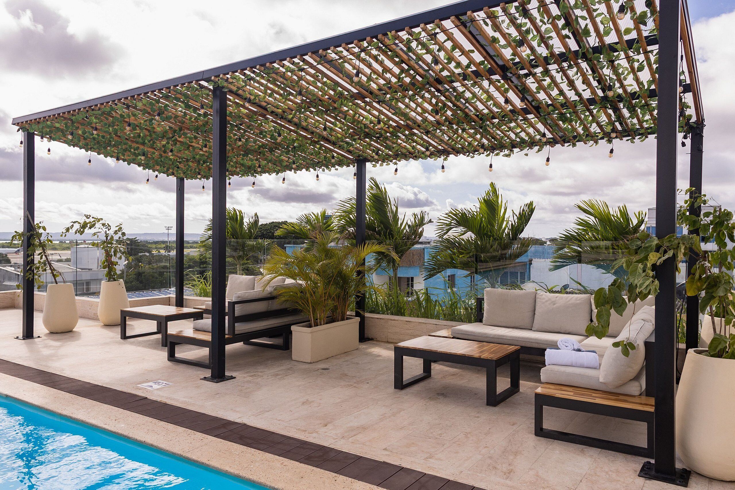 Un espace piscine sur le toit, avec des sièges d’extérieur, une pergola et des plantes en pot.