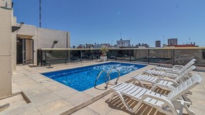 A rooftop pool with clear blue water, surrounded by white lounge chairs and a glass railing. - King Suite in Recoleta with Pool & Gym (Buenos Aires)