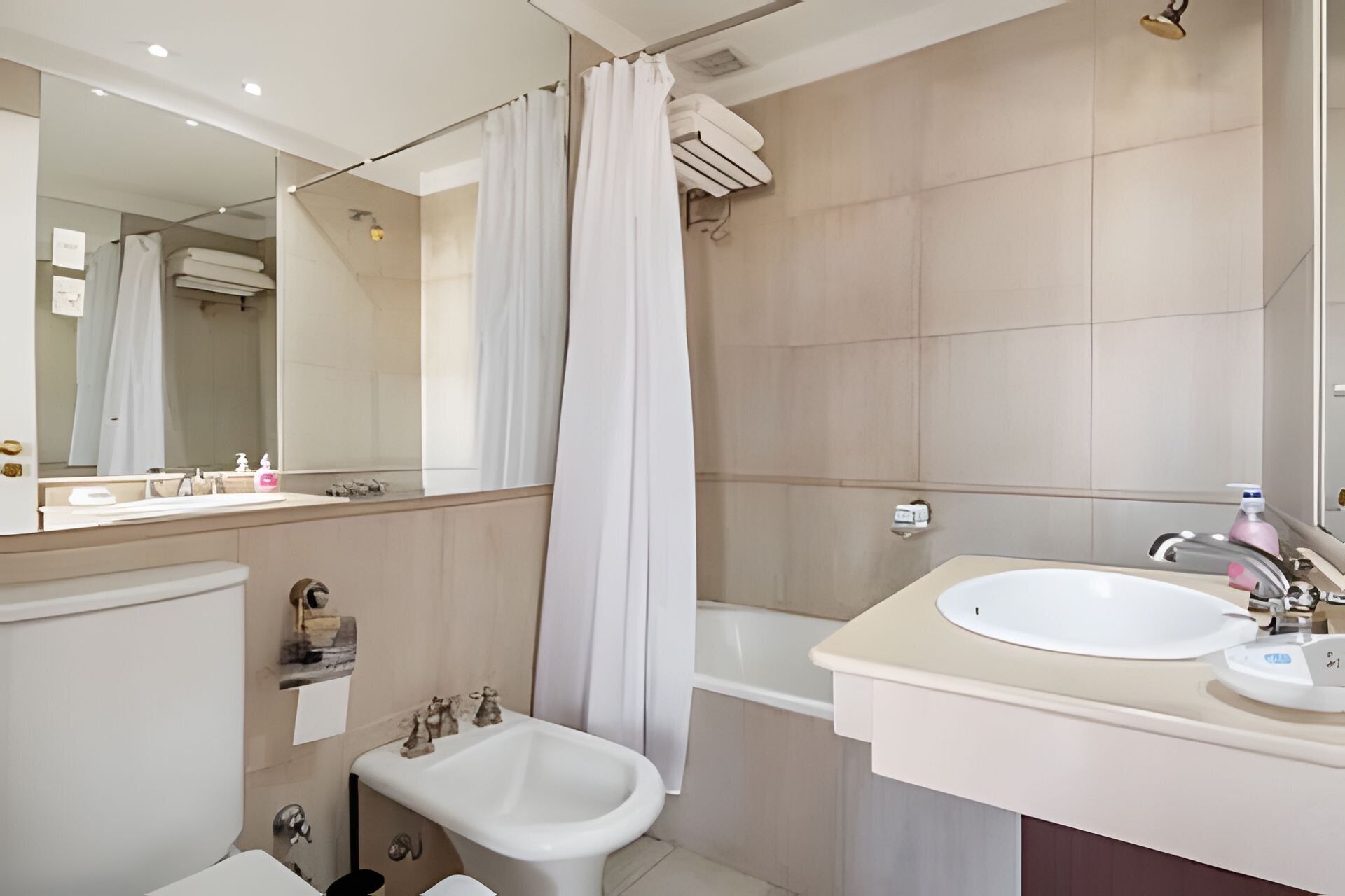 Une salle de bain moderne équipée d’une baignoire, d’un lavabo, d’un bidet et d’un rideau de douche.