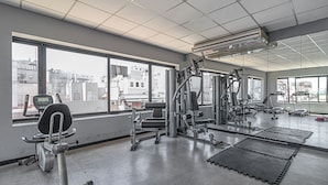 A gym with exercise equipment, large windows, and a view of buildings. - King Suite in Recoleta with Pool & Gym (Buenos Aires)