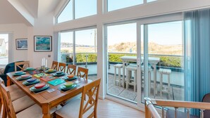 A dining area with a wooden table set for six, large windows, and a view of the outdoors. - 4 Bed in Instow (oc-i31748) (Instow)