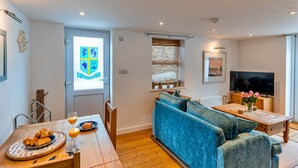 A living room with a blue sofa, wooden coffee table, and a TV. - Cottage in Porthleven Near Beach & Harbour (Helston)