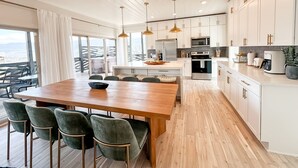 A modern kitchen with white cabinets, a wooden dining table, and green chairs. - Smoky Mountain Views / Luxury Escape (Gatlinburg)