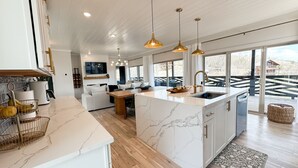 A modern kitchen with a marble island, wooden flooring, and pendant lighting. - Smoky Mountain Views / Luxury Escape (Gatlinburg)