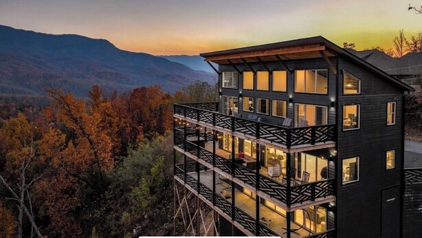 A multi-story building with a balcony, surrounded by autumn foliage and mountains. - Smoky Mountain Views / Luxury Escape (Gatlinburg)