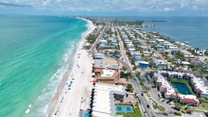Ein Luftbild eines Küstenresorts mit Strandhäusern, einer parallel zum Strand verlaufenden Straße und freiem Blick auf den Ozean.