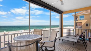 Ein Balkon mit Blick auf den Strand, inklusive Tisch, Stühlen und Deckenventilator.