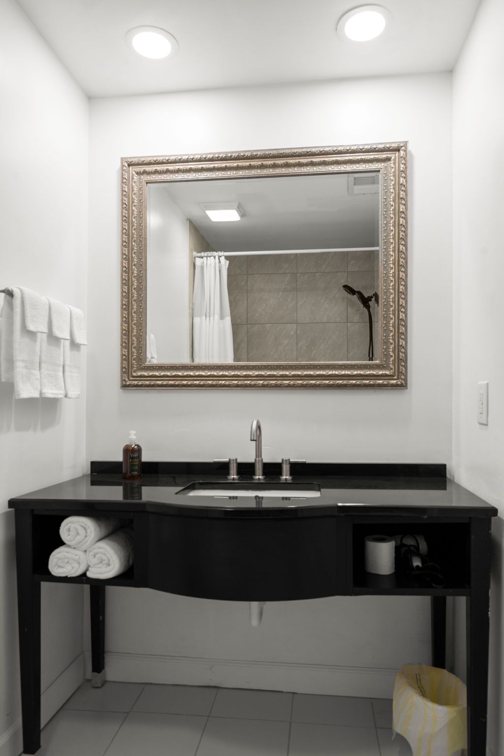 A modern bathroom with a large mirror, a black vanity, and a shower.
