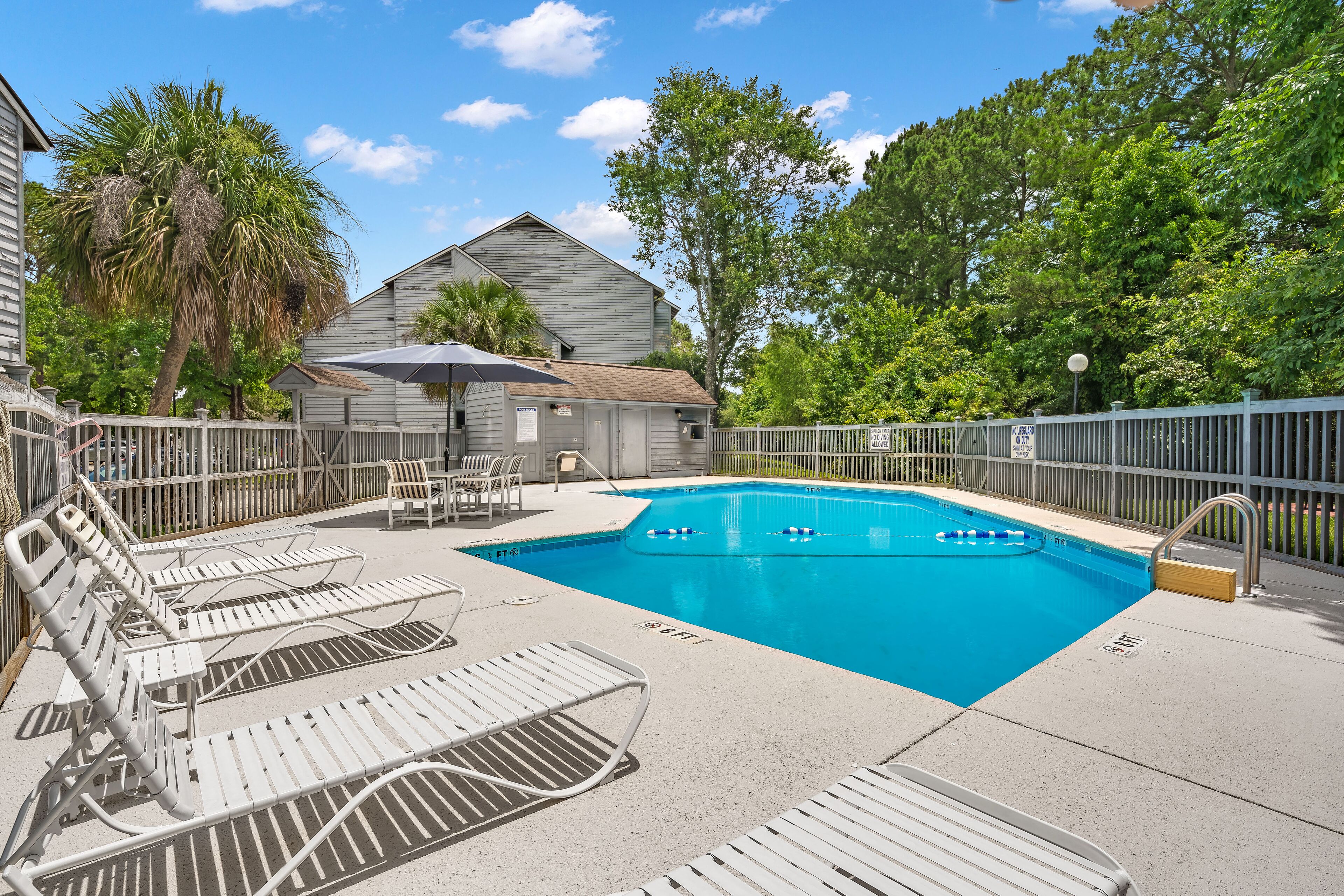 A swimming pool with lounge chairs and a wooden deck.