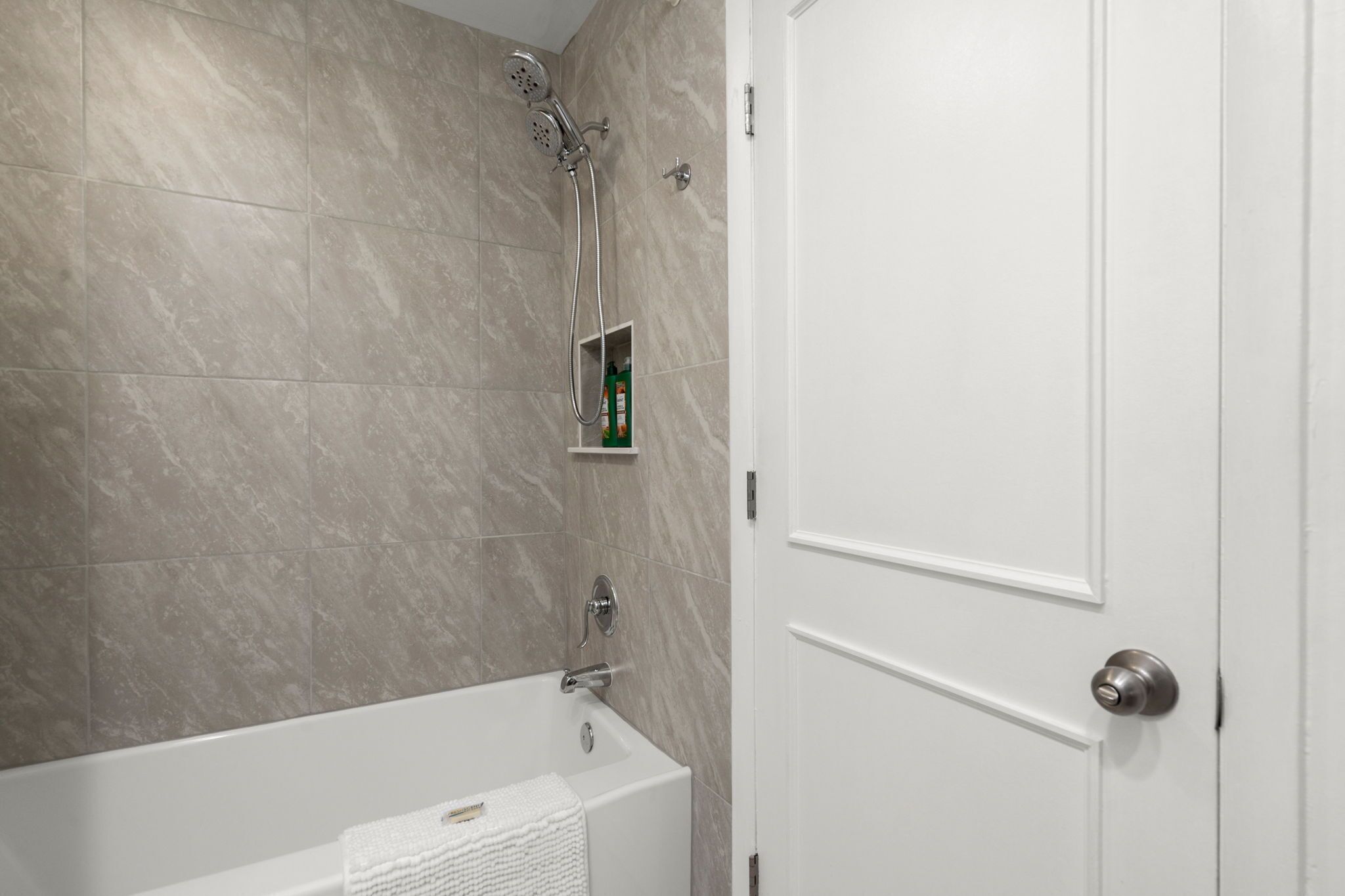 Ein Badezimmer mit Badewanne, Dusche und einer Tür.