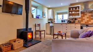 A cozy living room with a fireplace, a sofa, and a television. - Studio in Boscastle Near Tintagel Castle (Boscastle)