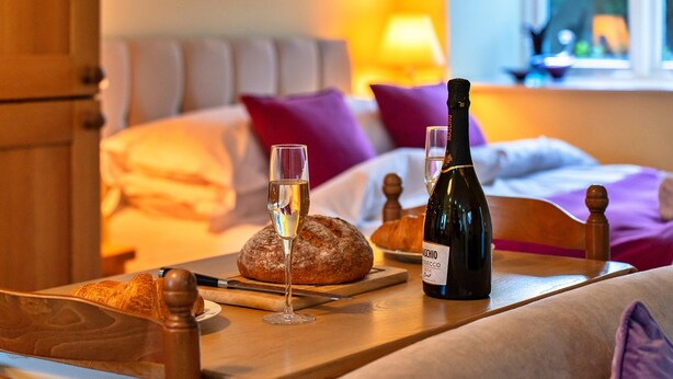 A cozy room with a bed, a wooden table with a bottle of wine, glasses, and a loaf of bread. - Studio in Boscastle Near Tintagel Castle (Boscastle)