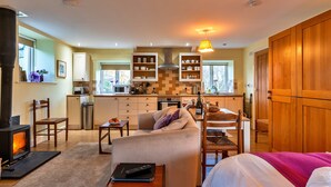 A cozy living room with a fireplace, a sofa, and a dining area. - Studio in Boscastle Near Tintagel Castle (Boscastle)