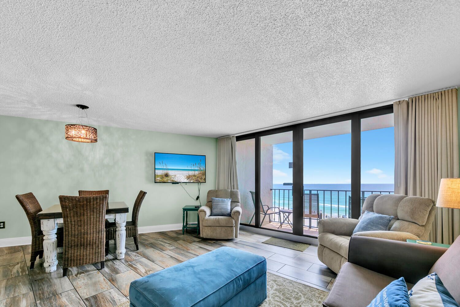 Ein geräumiges Wohnzimmer mit Essbereich, ein großes Fenster mit Blick auf den Strand und ein Balkon mit Meerblick.