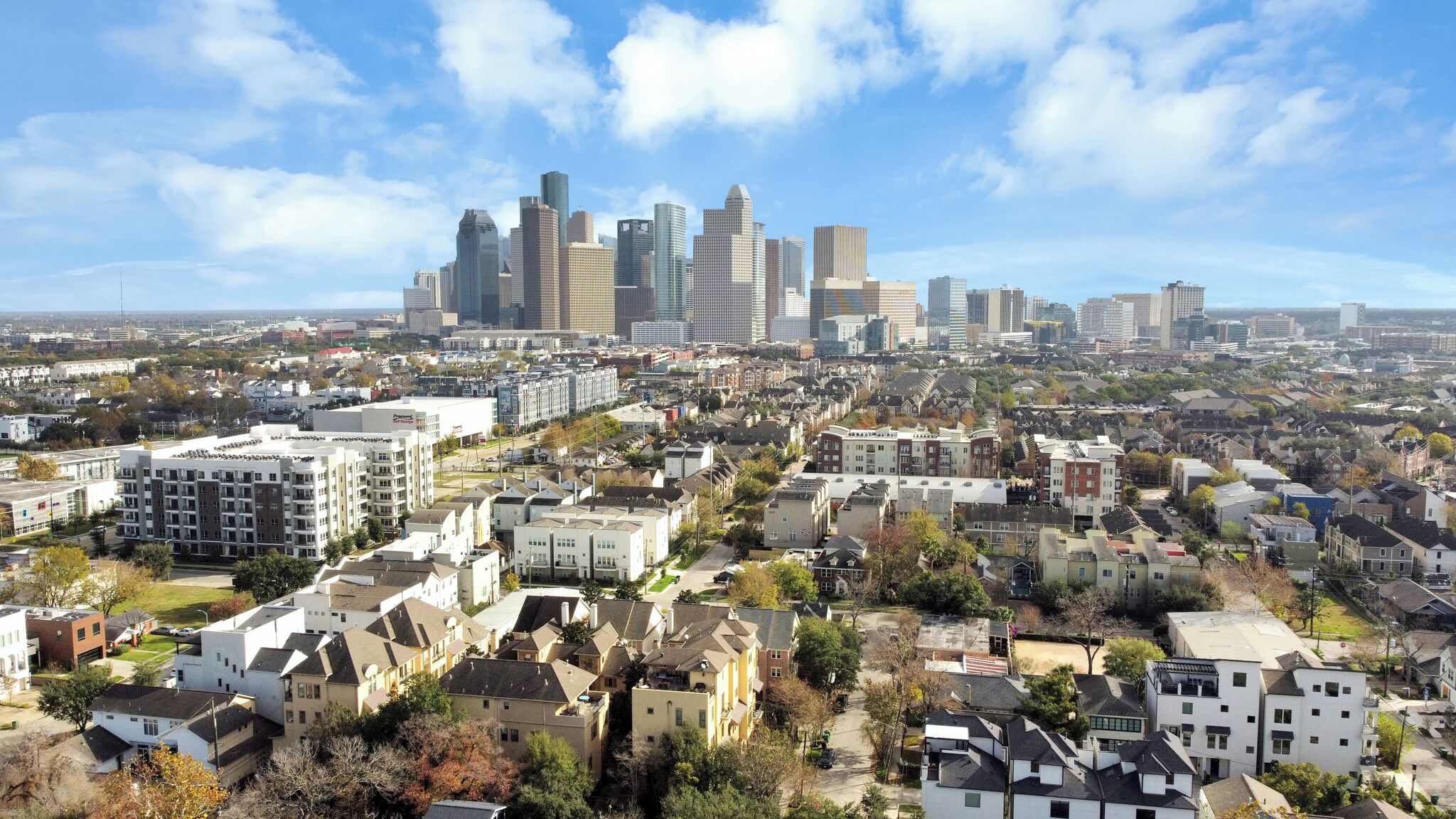 A cityscape with a prominent skyline of modern high-rise buildings in the background and a densely packed residential area in the foreground.