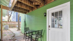 A covered patio with a green exterior wall, a white door, and a small table with chairs. - Your Perfect Private HideAway (Houston)