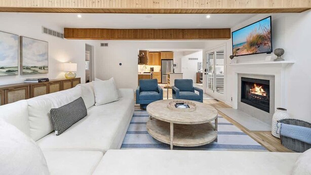 A modern living room with a sofa, chairs, a coffee table, a fireplace, and a television.