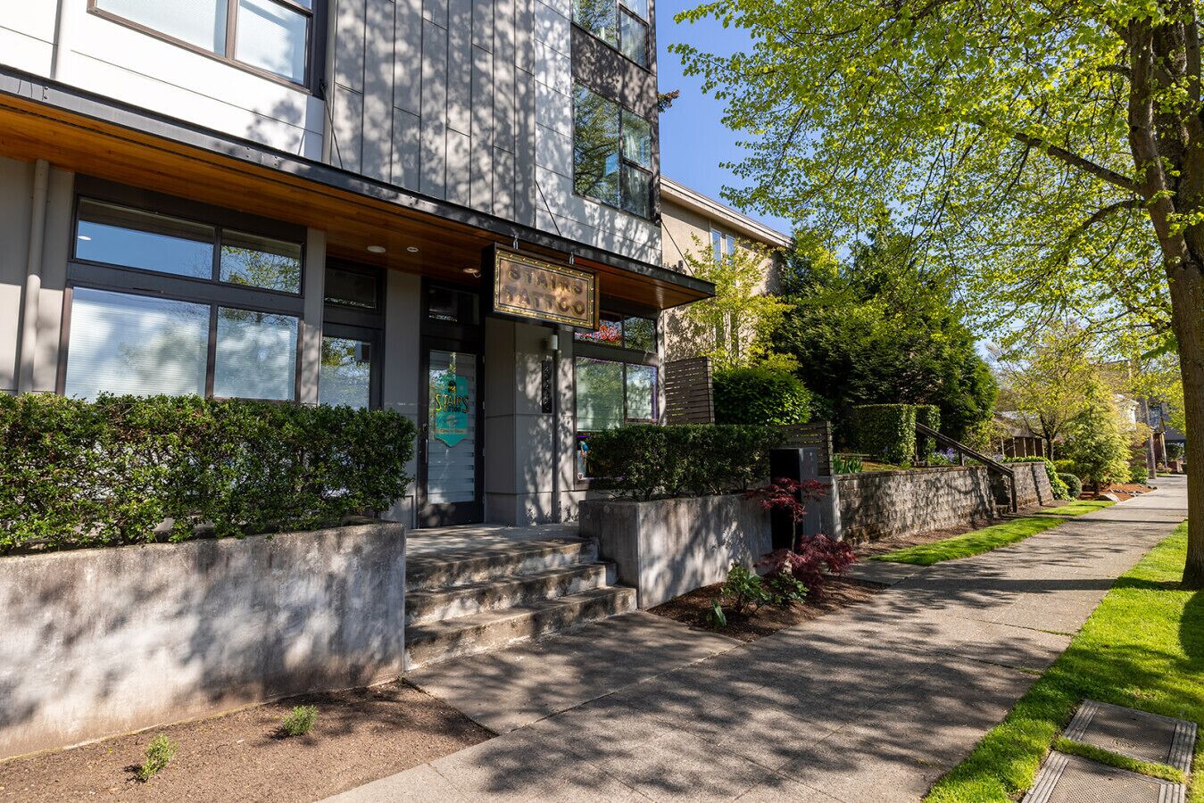 A modern building with a stone facade, large windows, and a well-maintained garden.