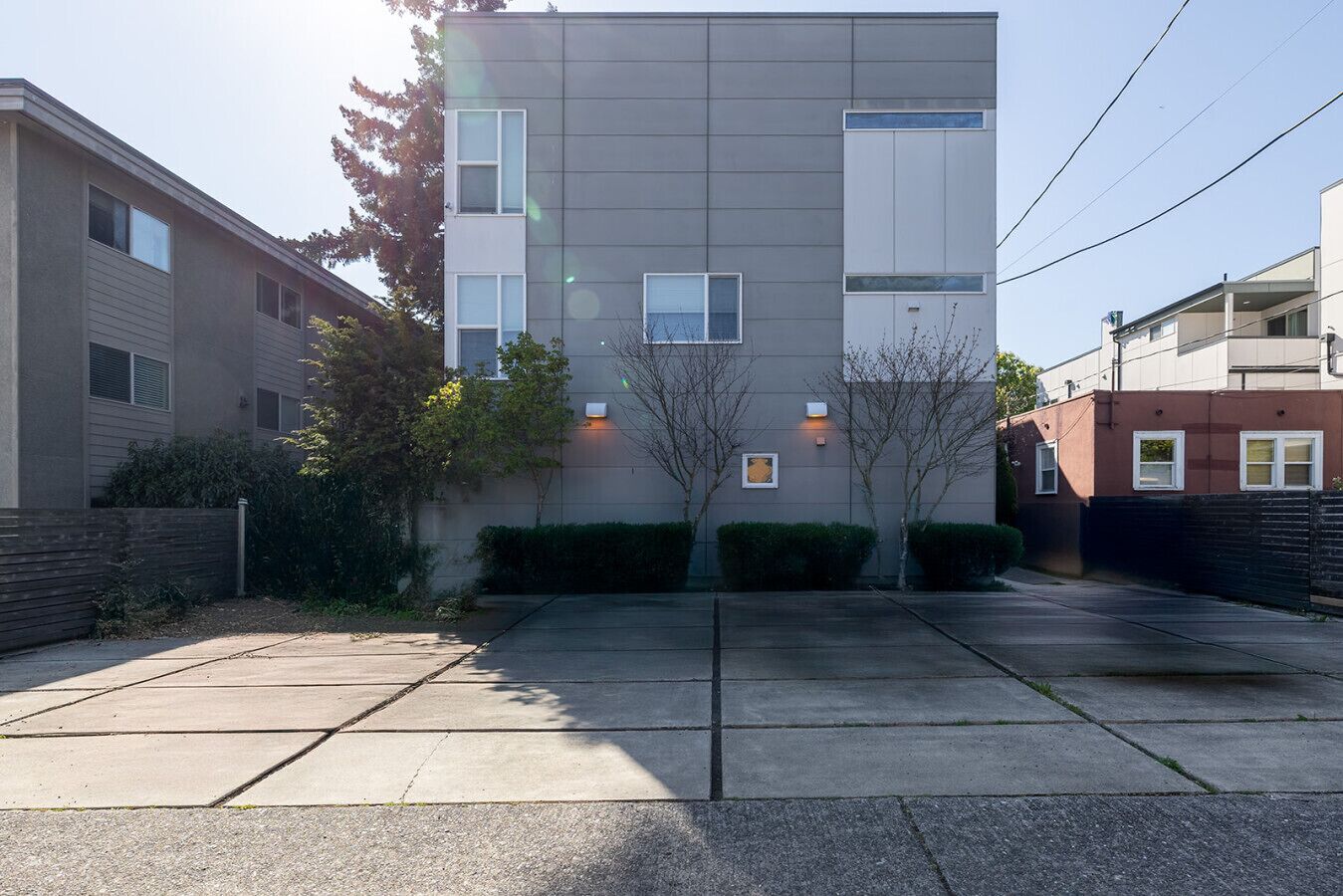 Un immeuble d’appartements moderne, doté d’une façade plate, de nombreuses fenêtres et d’une allée d’accès fermée par un portail.